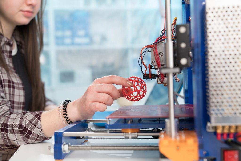Young woman print 3D model on 3D printer